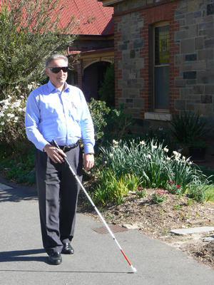 A man walking along a footpath using a white cane – Beyond Blindness